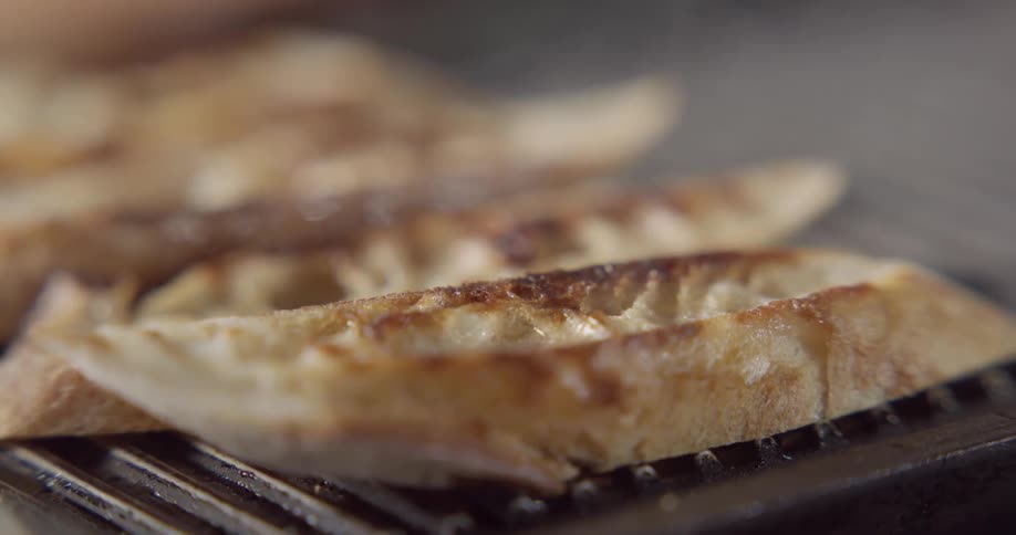 A person flips bread cooking on a grille