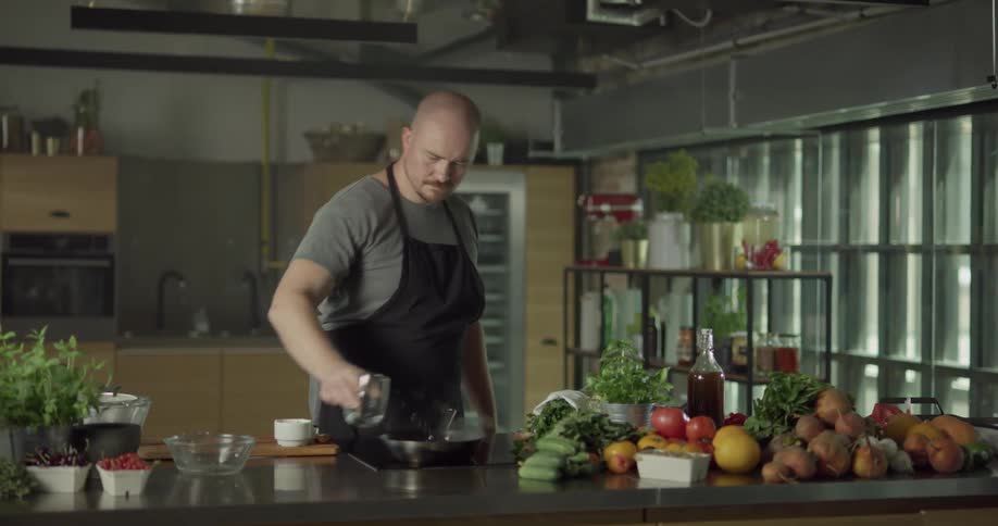 Chef pouring alcohol into a pan and setting in on fire