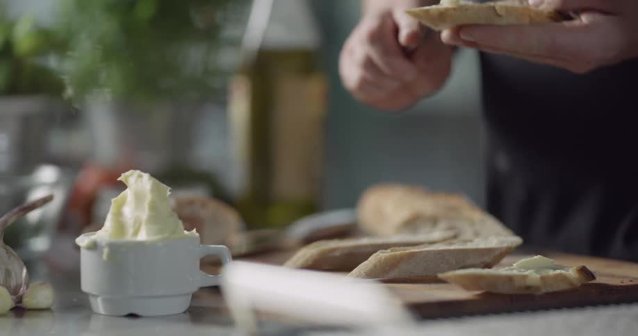 Butter being spread with a spoon on slices of narrow bread