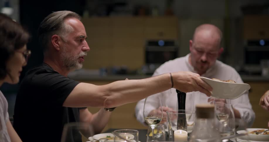 People take bread from a bowl being passed around during a friendly dinner party