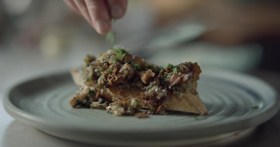 A plate of cooked chicken being garnished