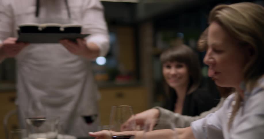 A chef delivers creme brulee to a table of people