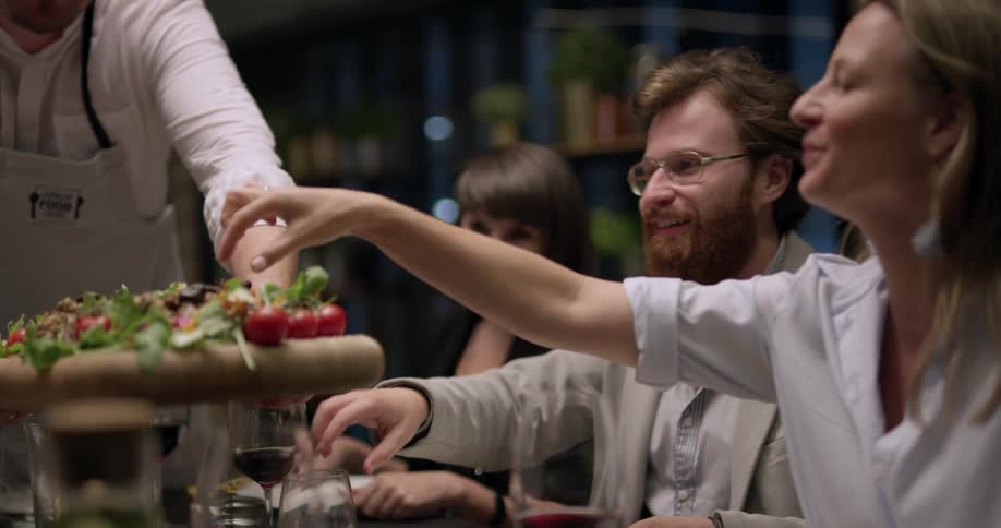 A chef brings out a salad to a group of people