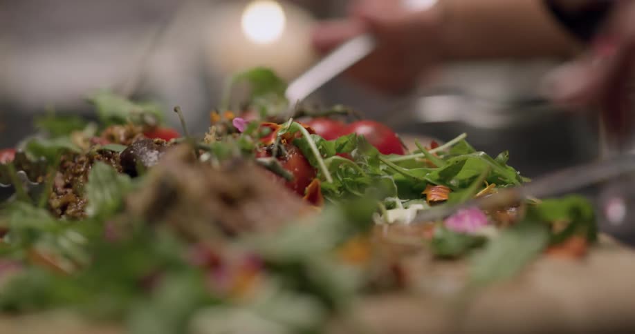 People grab salad off a cutting board