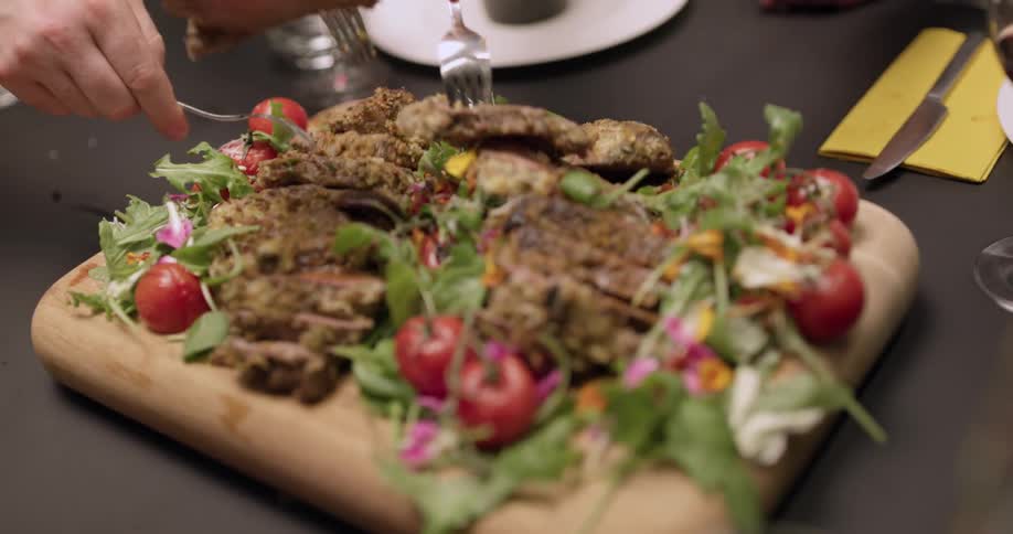 People are eating food from a cutting board in a restaurant