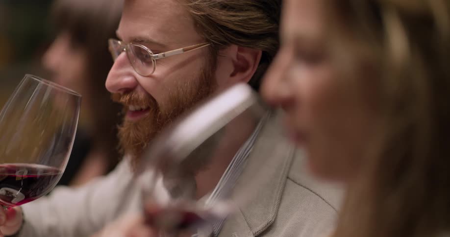 Man and woman sitting at dining table make a toast and laugh indoors