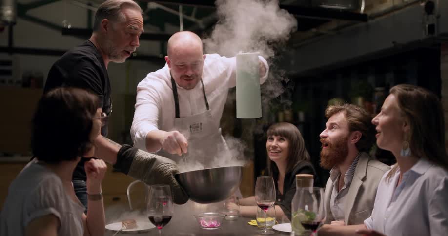 A chef is serving food to people at a table