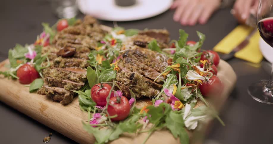 Food is displayed on a table with people sitting around it