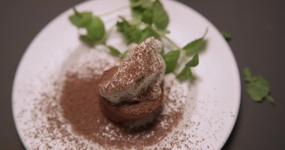 Chocolate dessert on a white plate with whipped cream and cocoa shavings