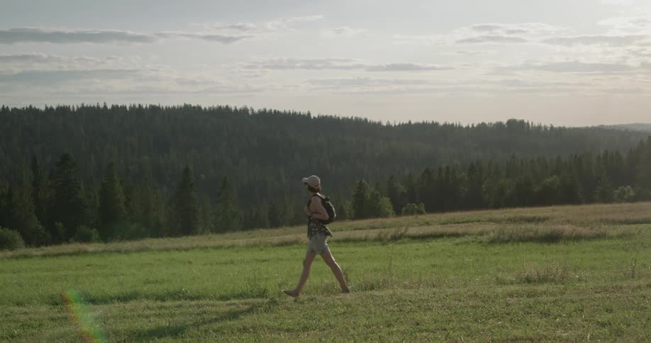 A female hiker walking through a field on a hillside