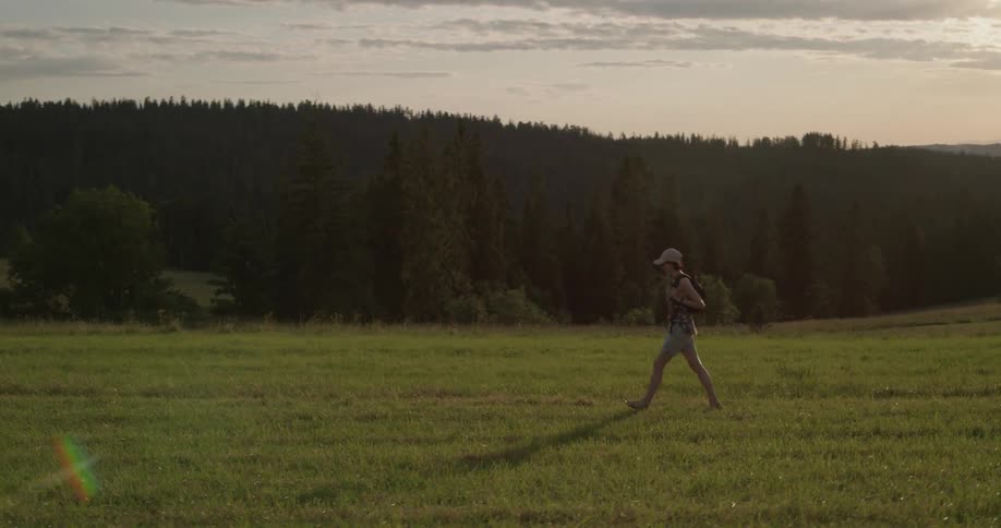 A woman hikes through a field at dusk