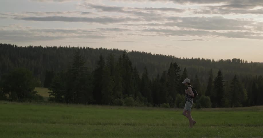 Woman wearing cap walks down in the forest by day