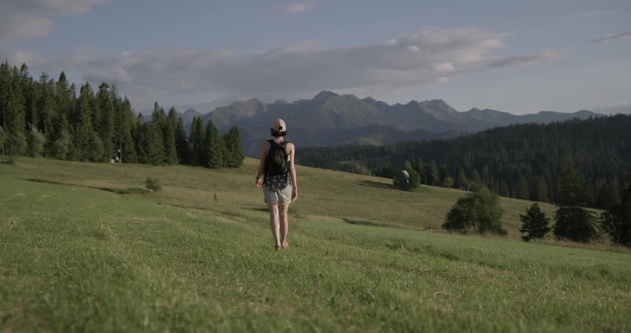 Woman with a backpack walks on a grassy field