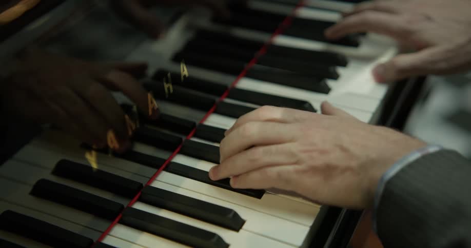 A man plays the piano with one hand crossed over the other for certain notes