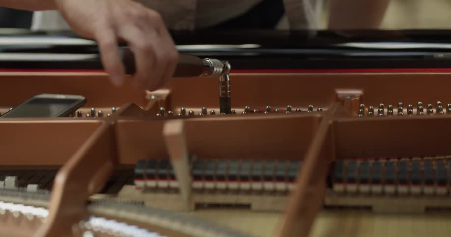A person tuning a piano with specialty tools
