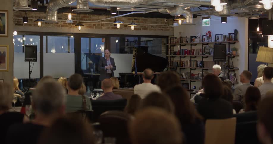 A man stands on a stage talking to an audience