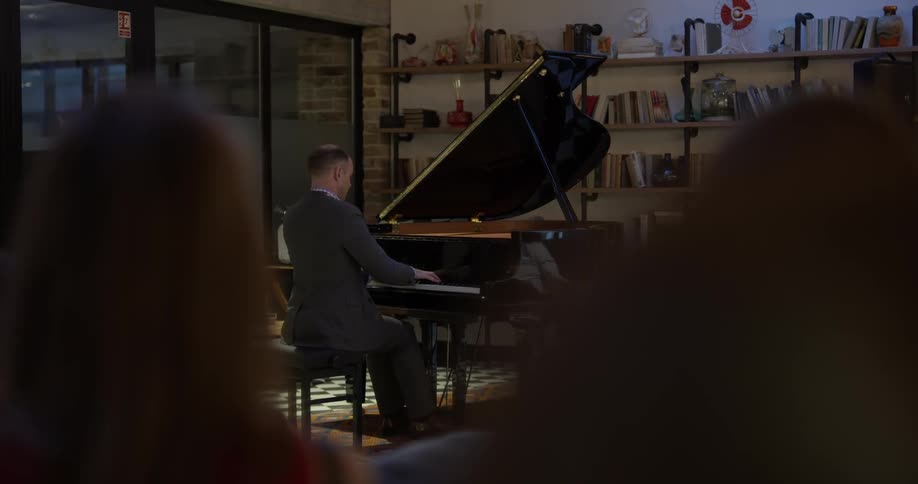 A man plays a grand piano in front of an audience