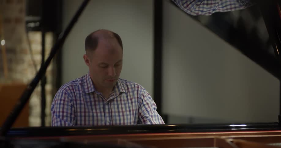 A man plays a grand piano at night