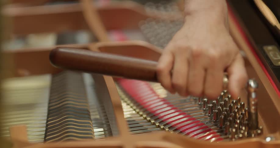 A piano tuner tunes a piano