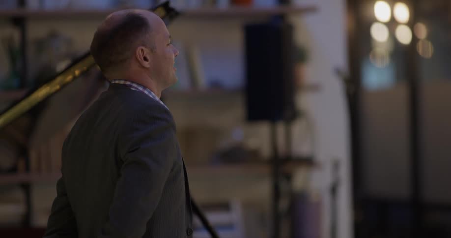 A pianist rises from his grand piano and bows to an audience
