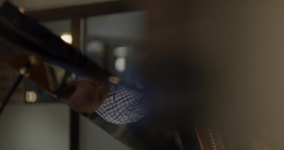 A bald man hunched over doing something with his hands