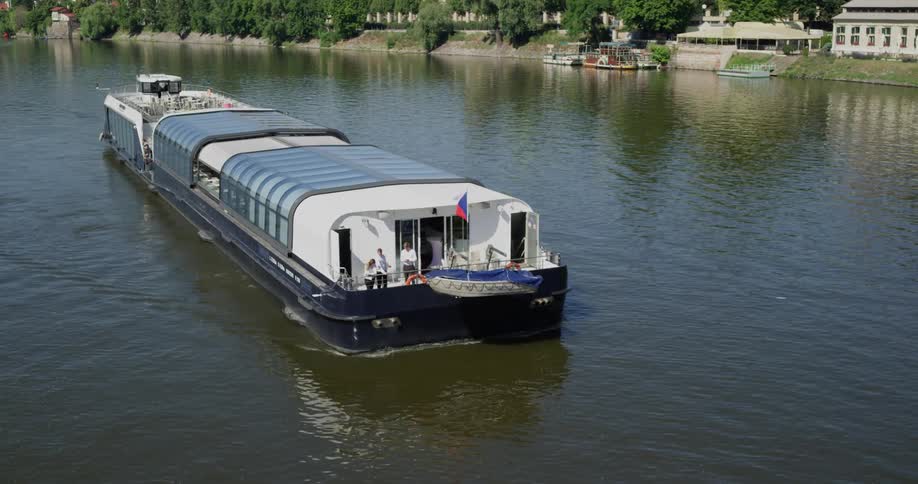 A barge traveling down a calm river during the day