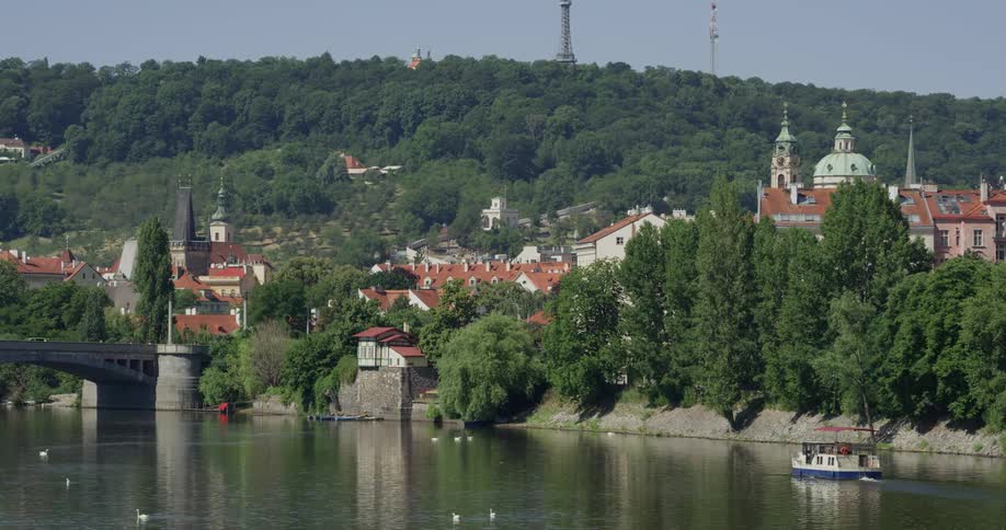 A passenger boat motors down a river near an old city