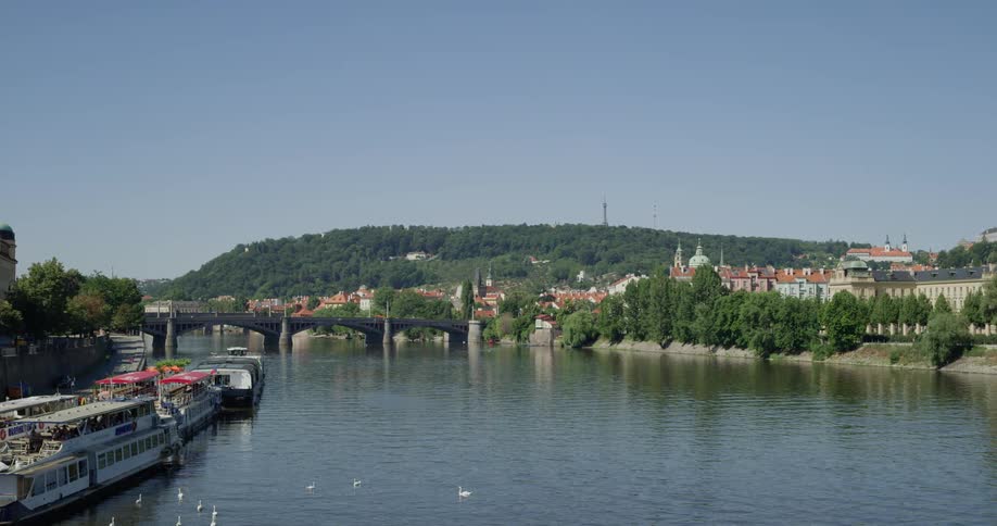The camera looks out over a river next to a city
