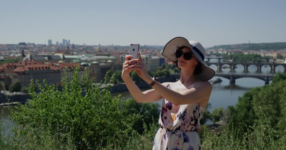 Female tourist wearing a big sun hat taking a selfie