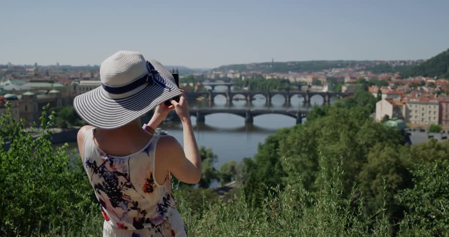 A woman with a smartphone taking a picture of a city