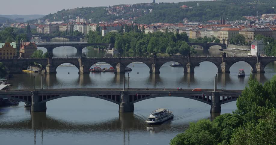 A boat passes along the water under a bridge