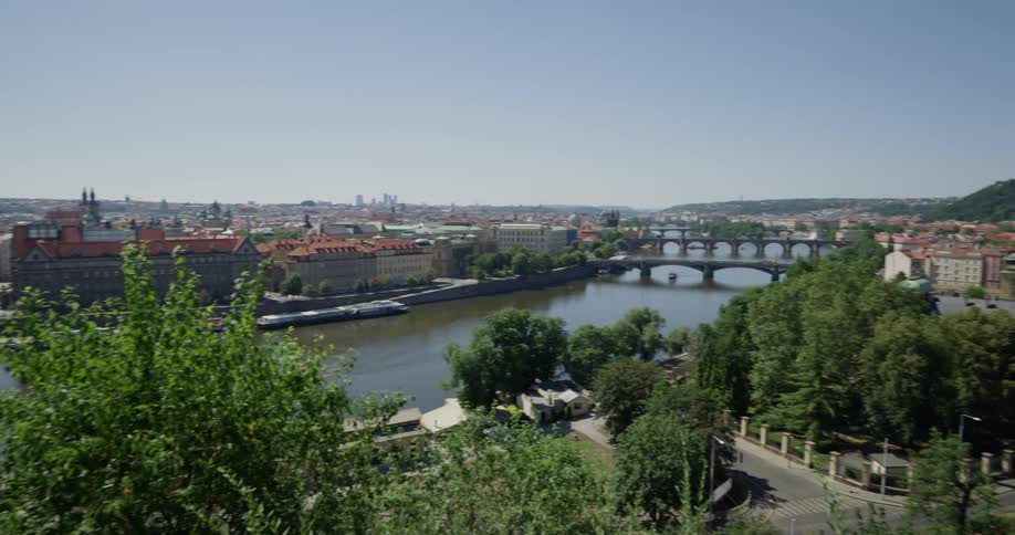 A city that is on a body of water near a highway trees and a bridge