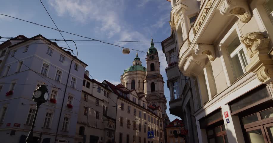Buildings lining a city street with trolley wires crossing the sky