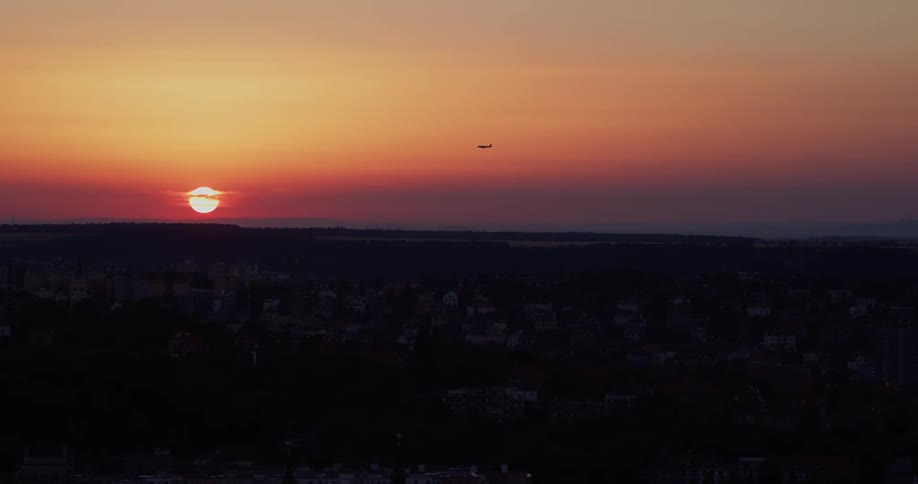 Airplane flies up in the air while the sun goes down