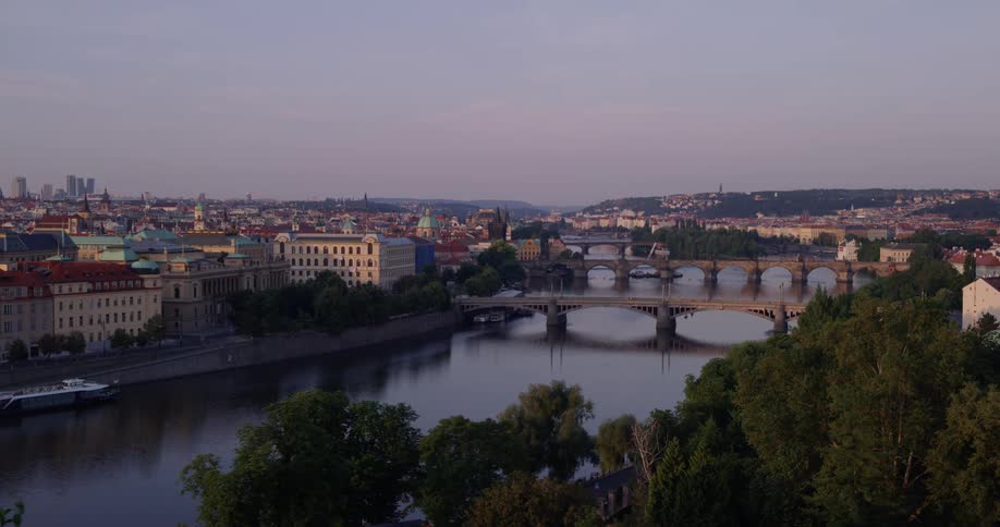 In a european city a calm river can be seen with a number of bridges crossing over it