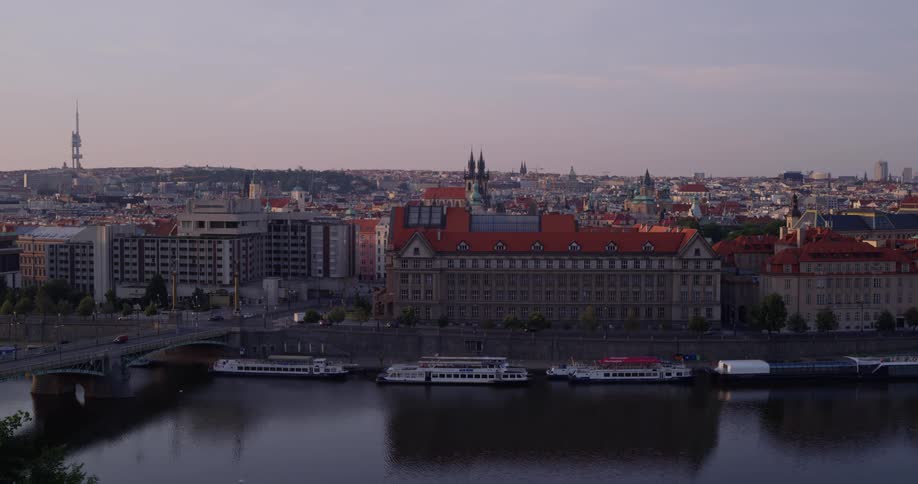 Large boats and ferries are docked on the side of a river next to a city