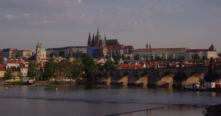 Buoys float on a river that flows under a stone bridge to a city
