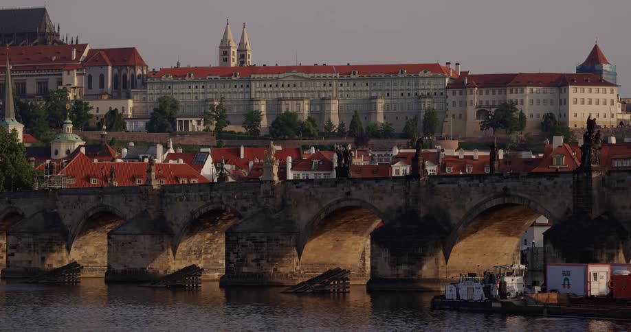 A old bridge over a river is located nearby a large building of classical architecture