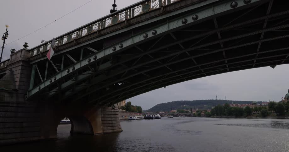 Traveling under an old stone and metal bridge on a canal