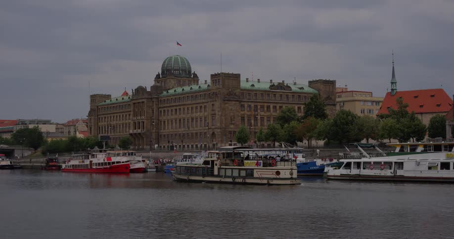 A ferry drives past docked ferries in a river next to a city