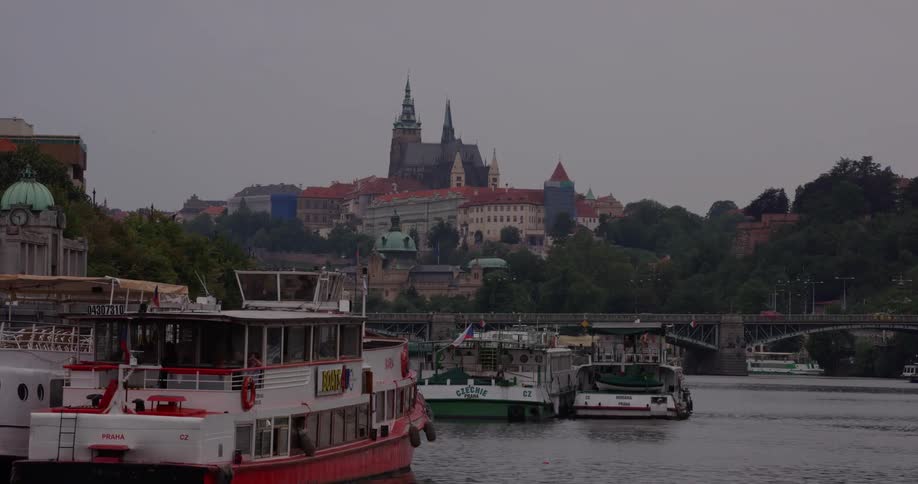 Boats on a river with buildings in the background on a hill