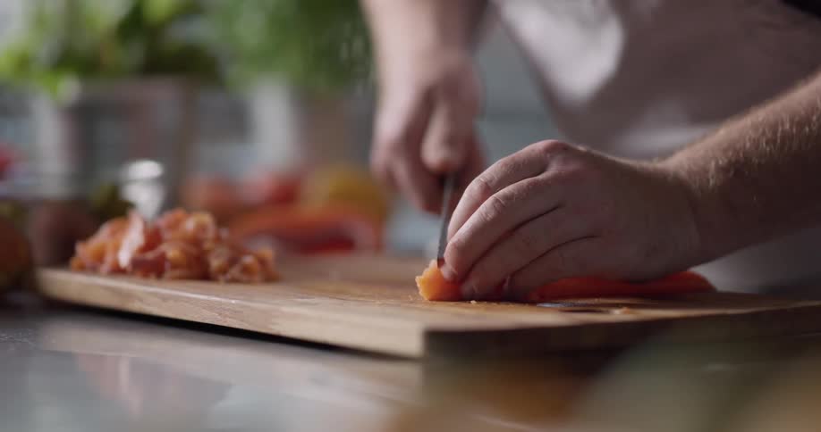 A fish fillet being sliced into strips on a wooden cutting board