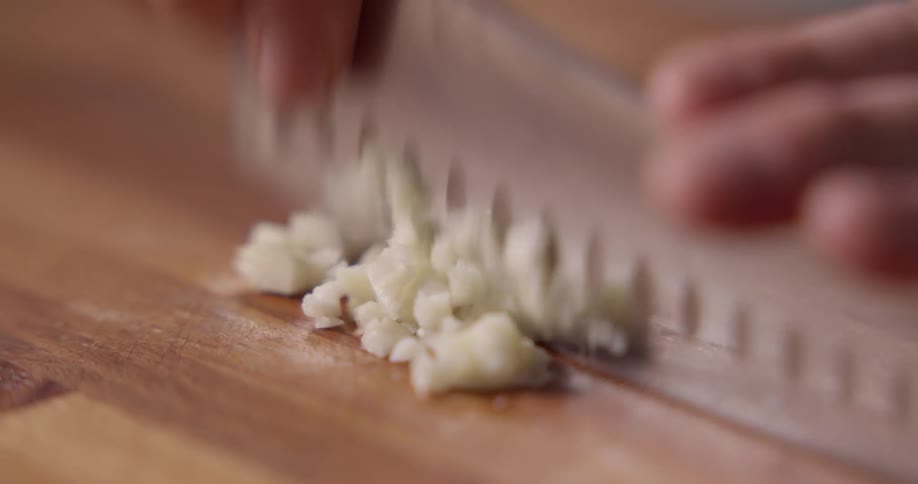 A person is chopping up garlic into small pieces