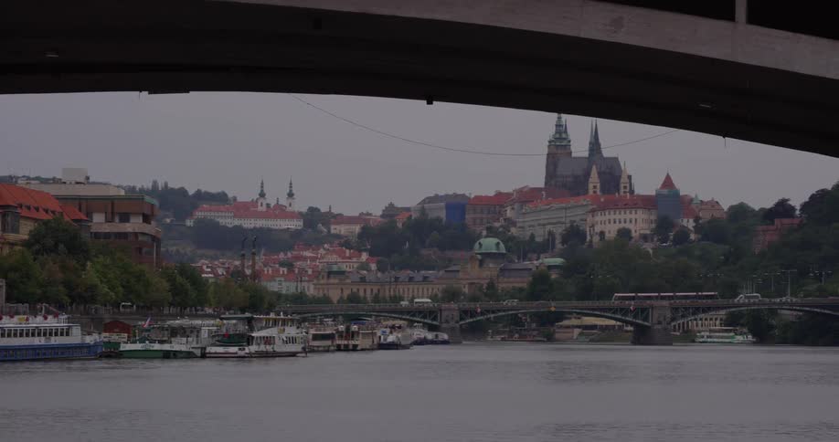 Cars and a bus travel over a bridge visible from under another bridge on the same river