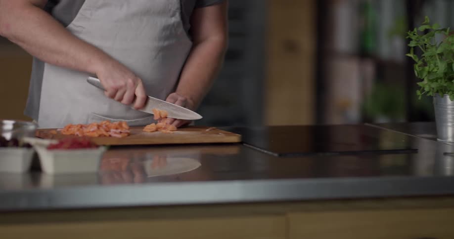 A white male slices a carrot on a wood cutting board in a kitchen