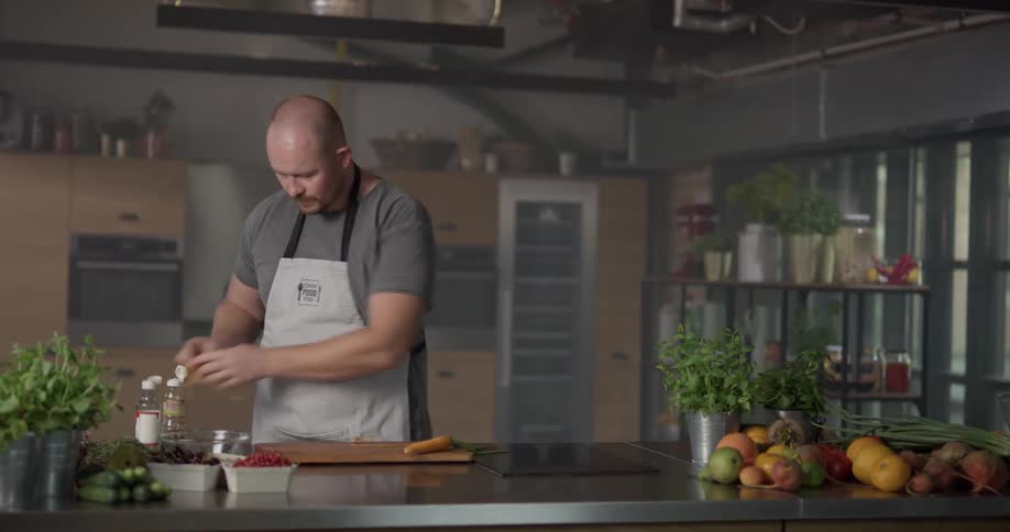 Male cook shredding a carrot on cutting board discarding skin then slicing ends off