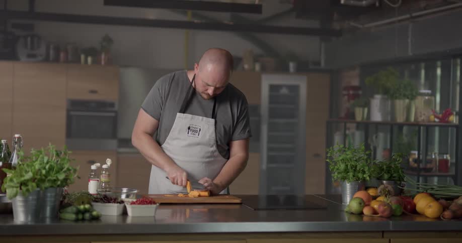 Man cuts on chopping board in restaurant kitchen