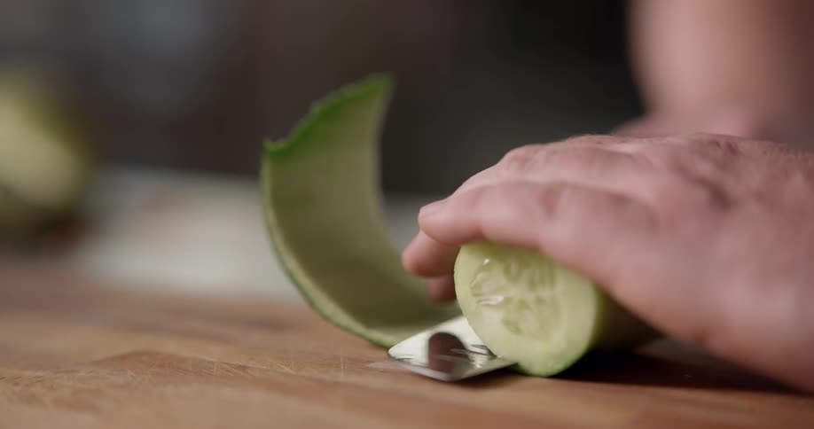 A zucchini being peeled with a knife