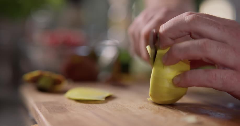 A person cuts slices off a vegetable on a cutting board