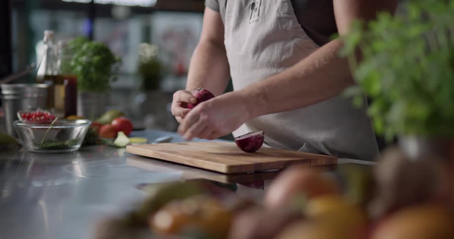 Man chops onion on chopping board